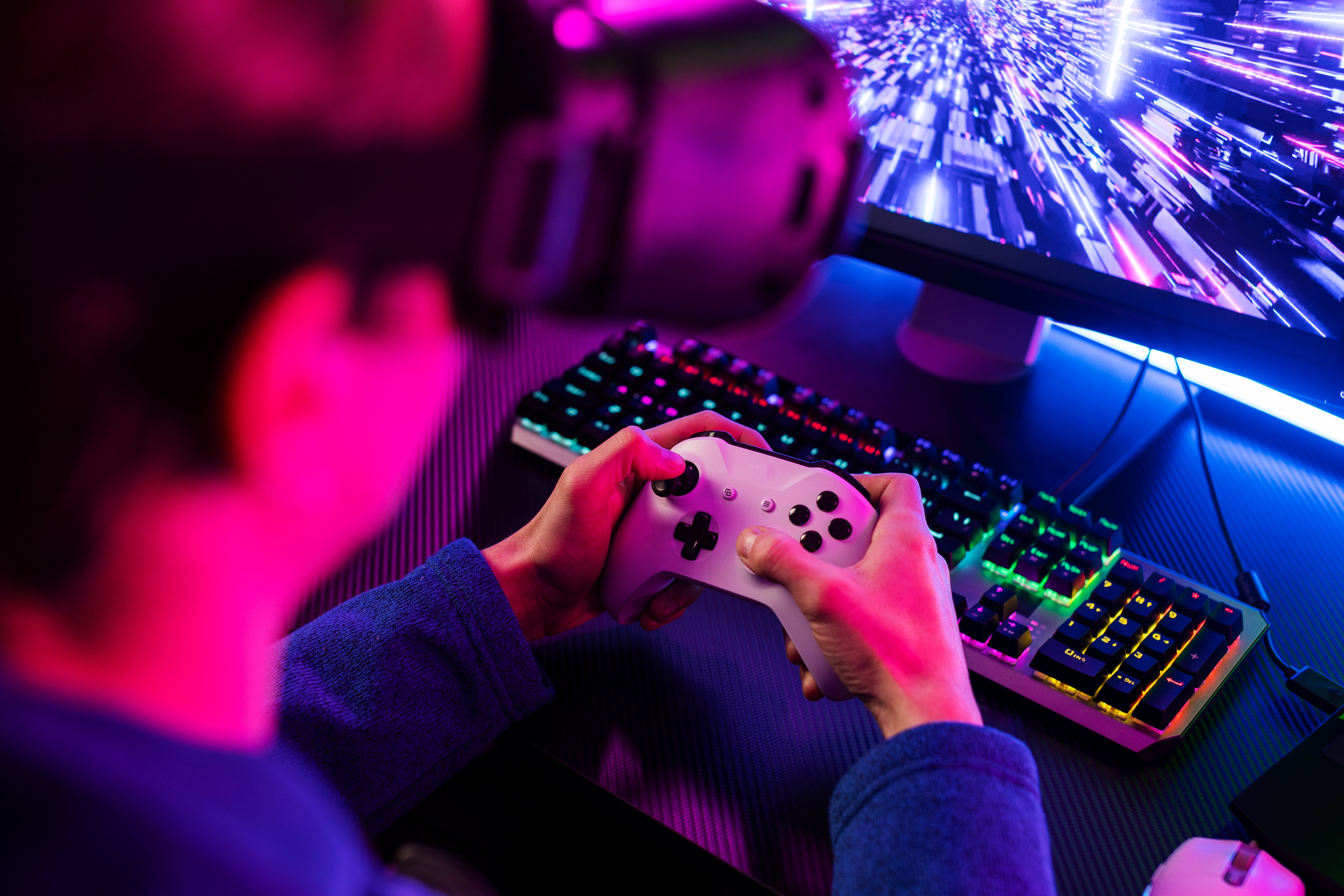 Imagem contendo um rapaz segurando um controle de videogame branco e usando um óculos de realidade virtual, enquanto joga.