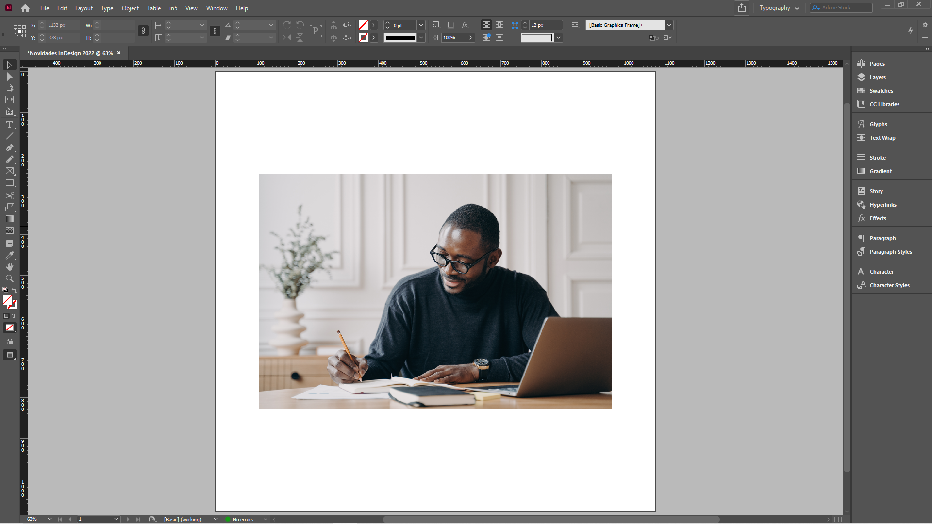 Imagem que mostra a interface do InDesign, com uma fotografia de um homem sentado à mesa, com um computador e escrevendo em um caderno, com a dimensão “small” acionada.