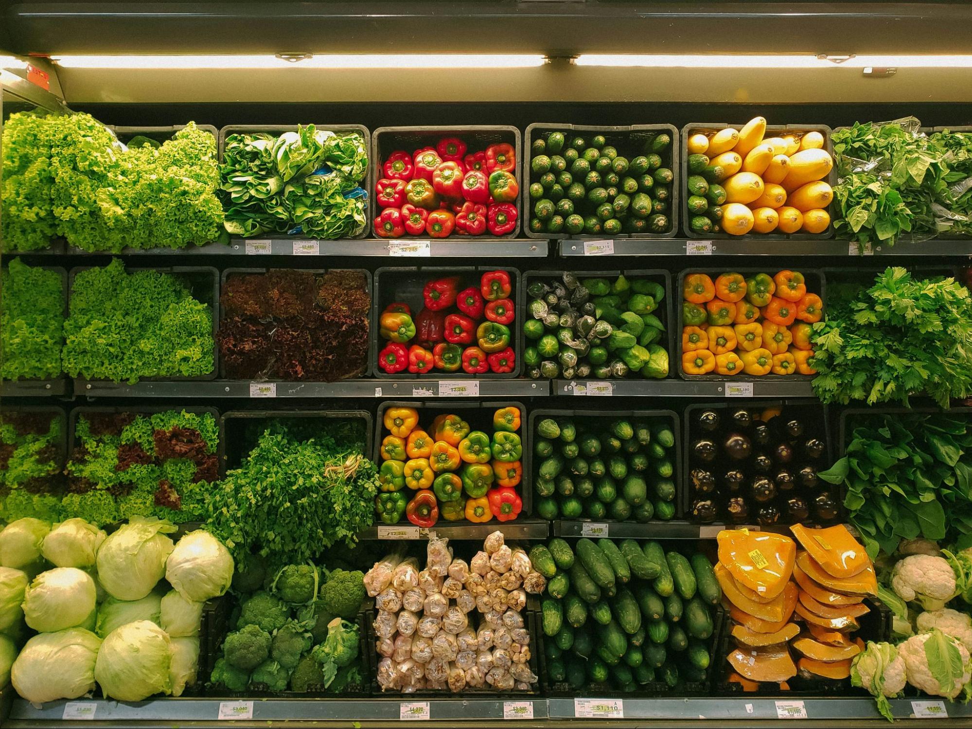 Fotografia de uma seção de hortifrúti em um supermercado, mostrando a diversidade de produtos frescos disponíveis para os consumidores.