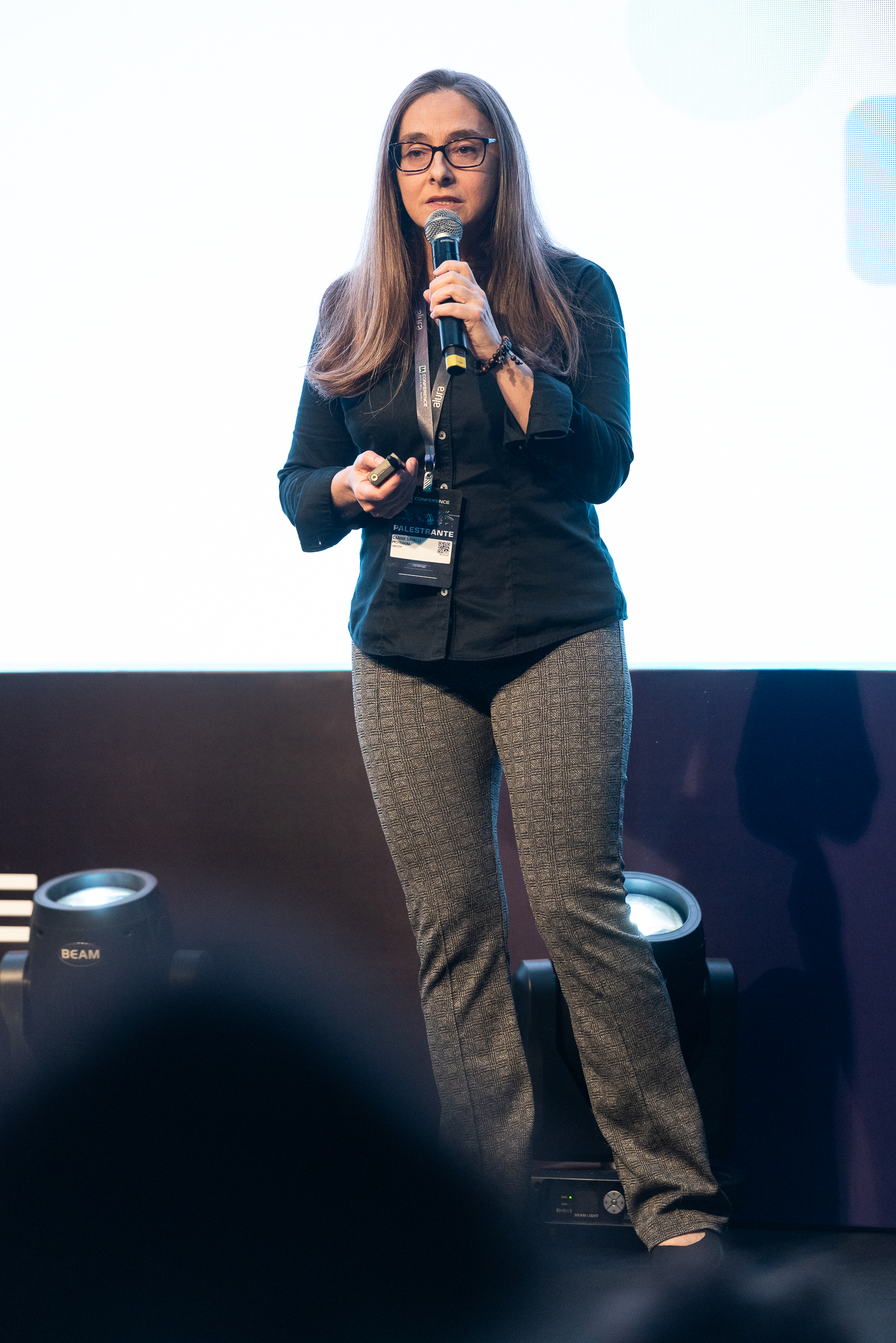 Na fotografia, Carine está no palco do IACB, com calça cinza e camiseta azul